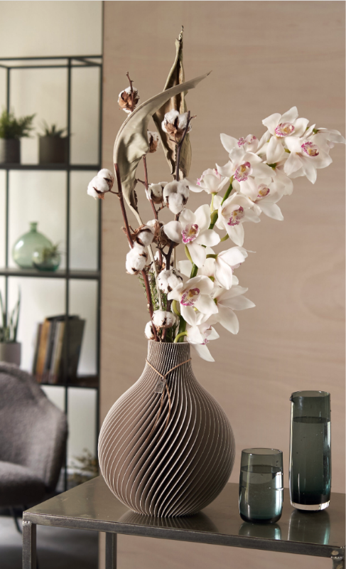Un vaso Sphere con fiori bianchi di cymbidium e rami di cotone su un tavolino scuro.